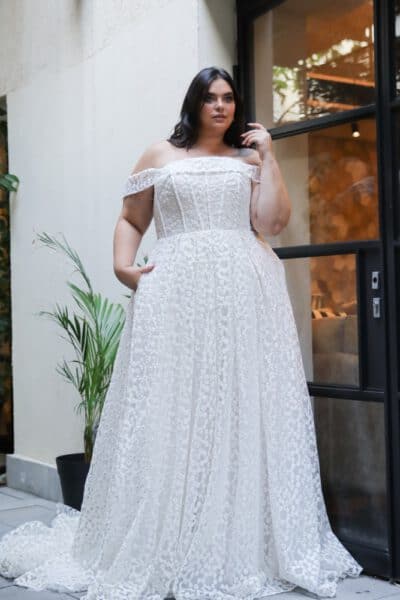 Plus-size bride in an off-the-shoulder lace wedding gown with a corset bodice and floral details
