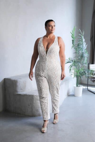 Plus-size bride in a lace bridal jumpsuit with a deep V-neckline and fitted silhouette