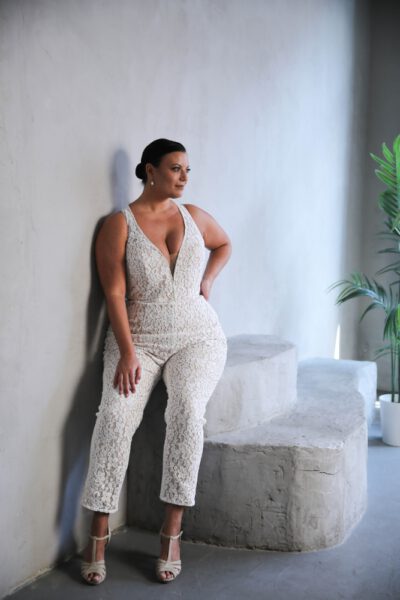 Plus-size bride in a lace bridal jumpsuit with a deep V-neckline and fitted silhouette