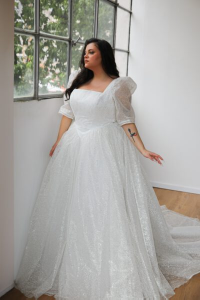 Plus-size bride in a glittering ball gown with a square neckline and puff sleeves