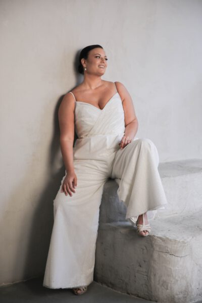 Plus-size bride in a chic bridal jumpsuit with spaghetti straps and wide-leg pants, showcasing a modern and stylish wedding look.