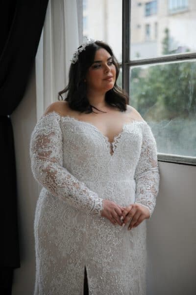Plus-size bride in a lace wedding gown with long sleeves, a deep sweetheart neckline, and intricate detailing