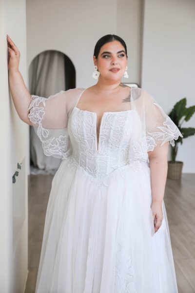 Plus-size bride in floral embroidered gown.