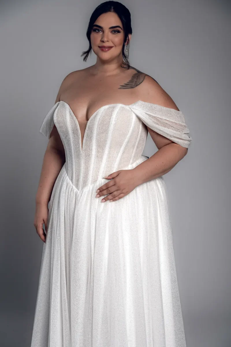 Studio Levana Anais plus size sparkly A-line wedding dress with sparkling fabric and an off-the-shoulder neckline, front three-quarter view