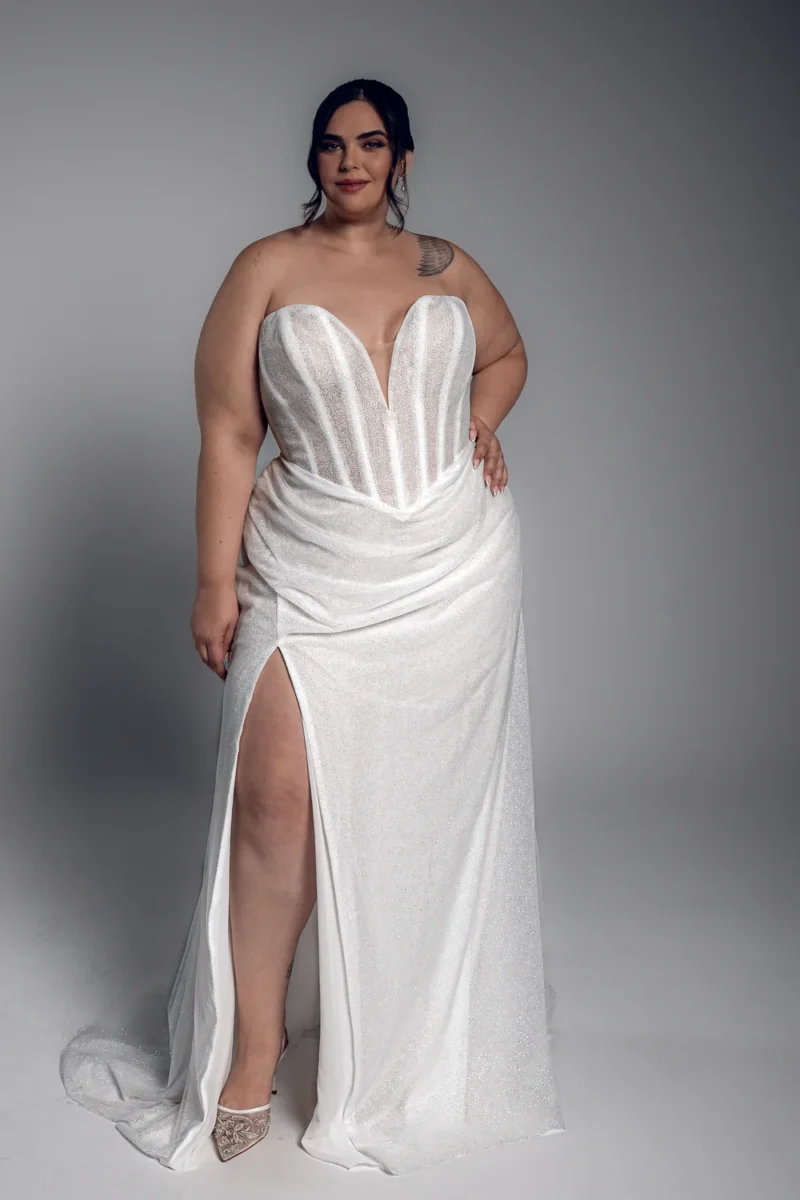 Studio Levana Anaise plus size sparkly fitted wedding dress with sparkling fabric and a strapless corset and a thigh-high slit, full-length front view