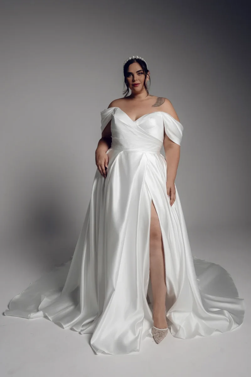Studio Levana Camille plus size A-line satin wedding dress with satin fabric and an off-the-shoulder neckline and a thigh-high slit, full-length front view