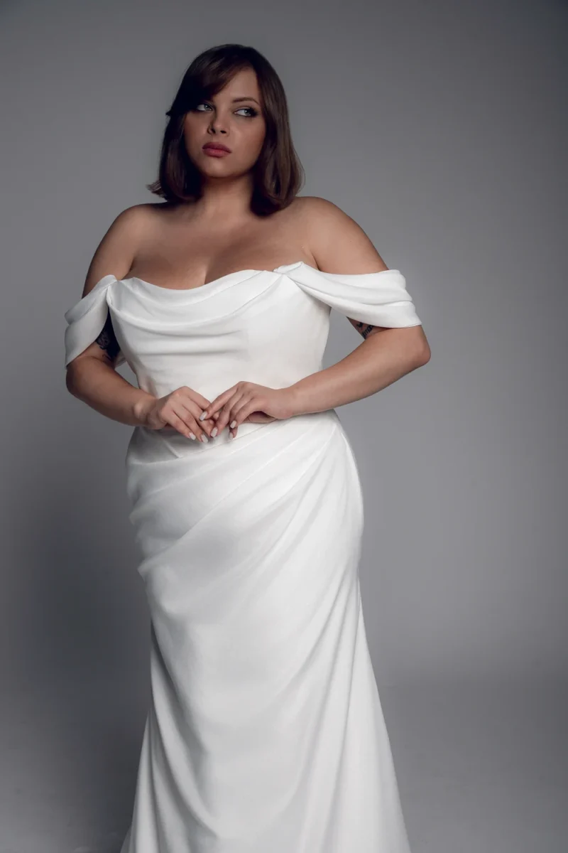 Studio Levana Ninon plus size satin fitted wedding dress with draped satin and an off-the-shoulder neckline, front three-quarter view