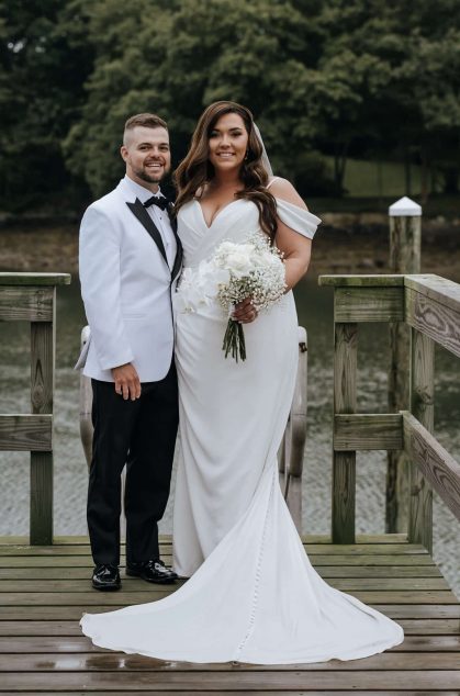 Bride and groom smiling on wooden dock by lake